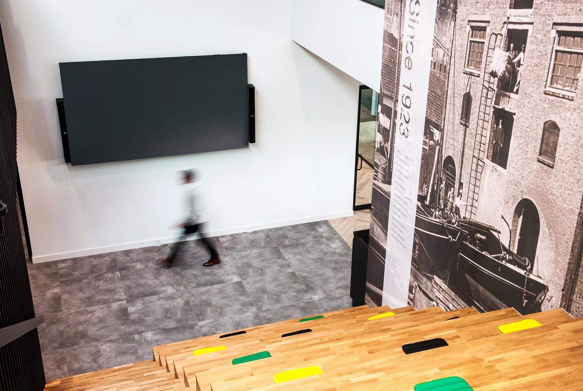 Hallway of the LC Packaging office with Panaray MSA12X steerable array loudspeakers installed next to a TV.