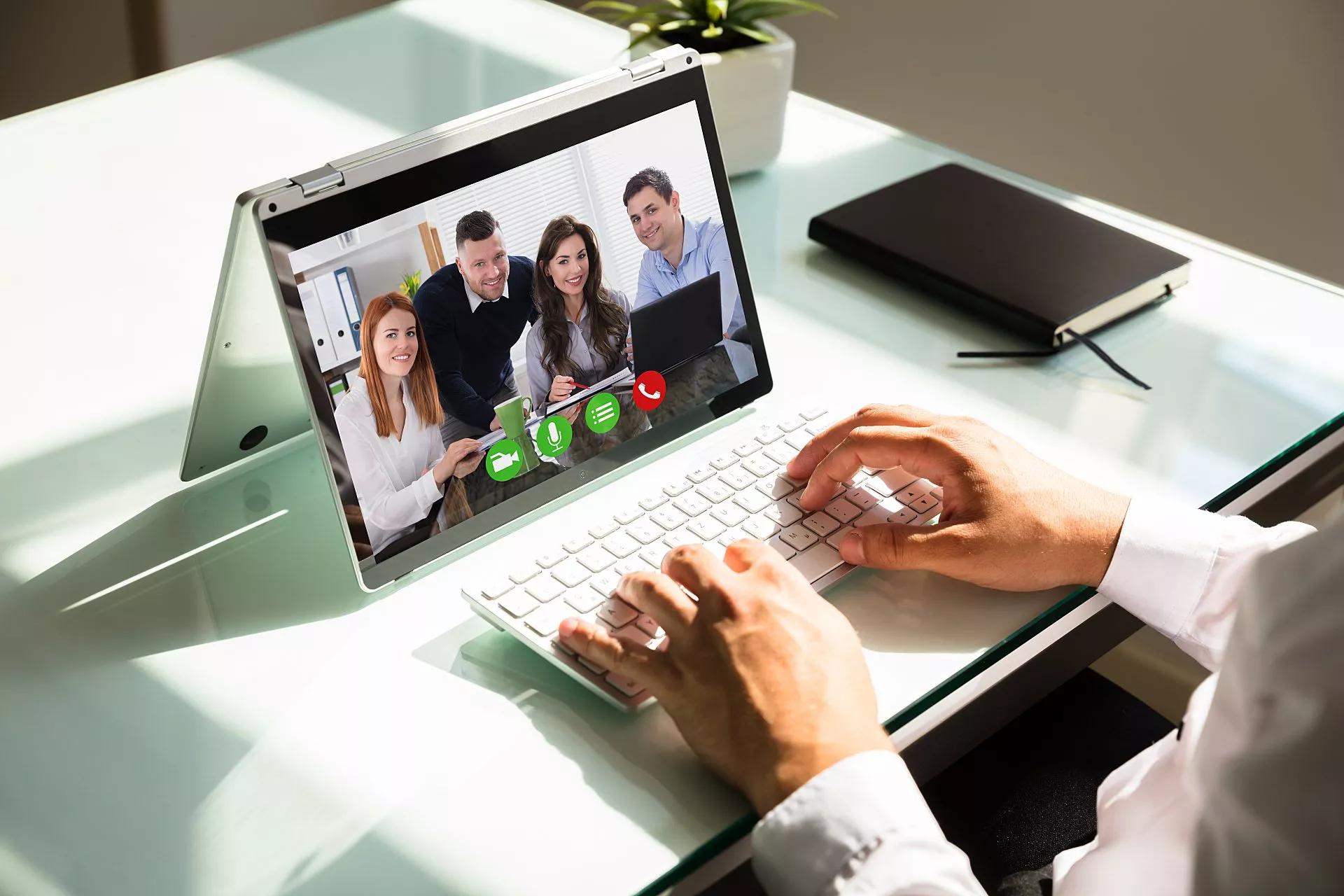A hybrid worker collaborates with his in-office colleagues using a tablet with video conferencing.