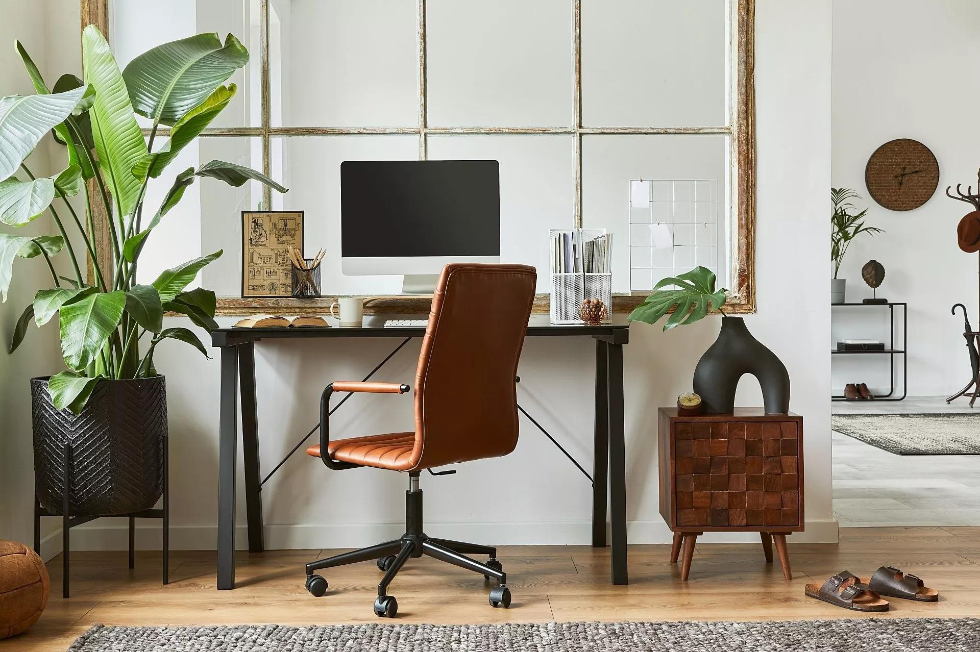 Well-lit modern workspace at home with desk, chair, white walls, and greenery.