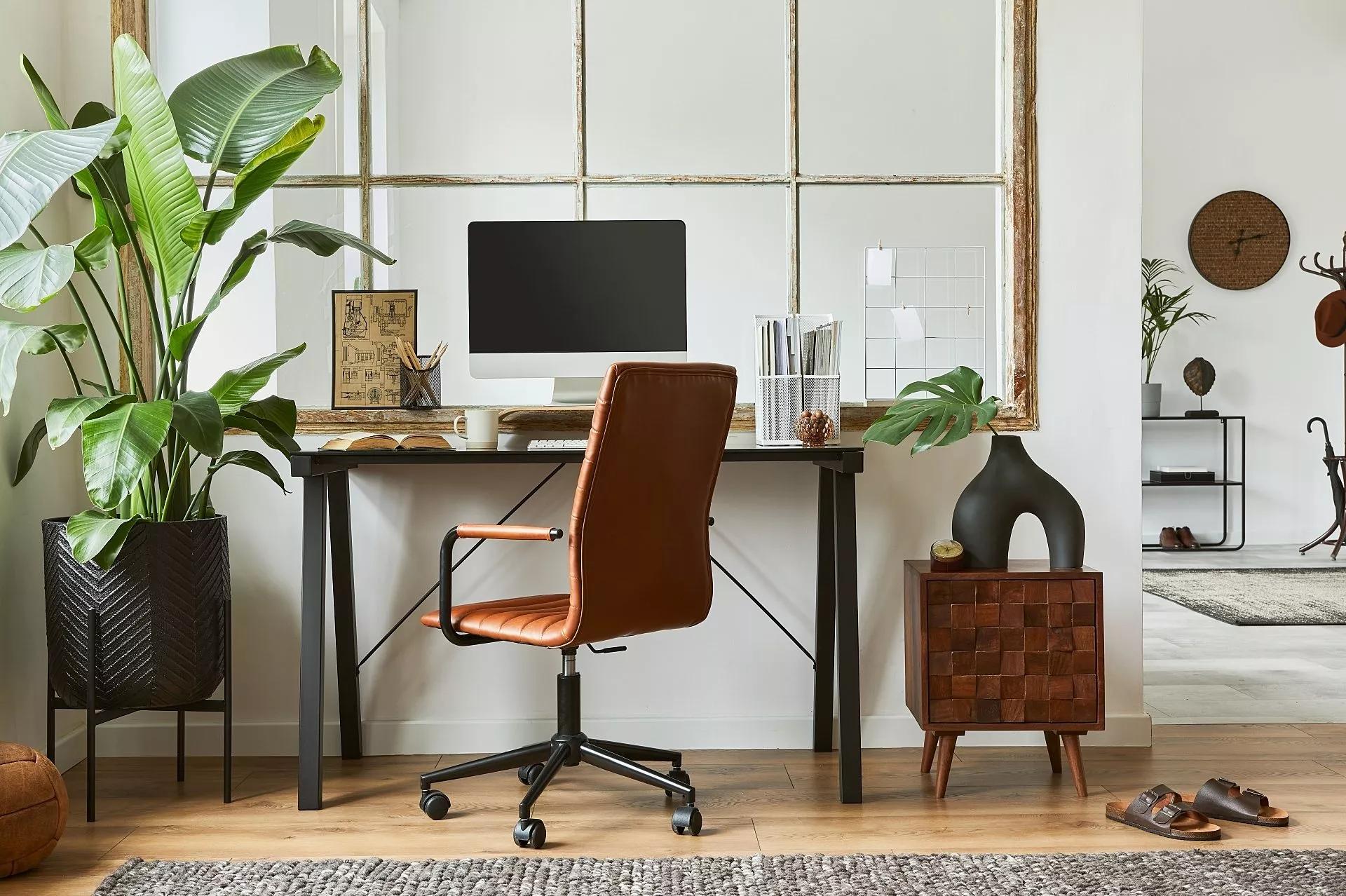 Espace de travail moderne et bien éclairé à la maison avec un bureau, une chaise, des murs blancs et de la verdure.