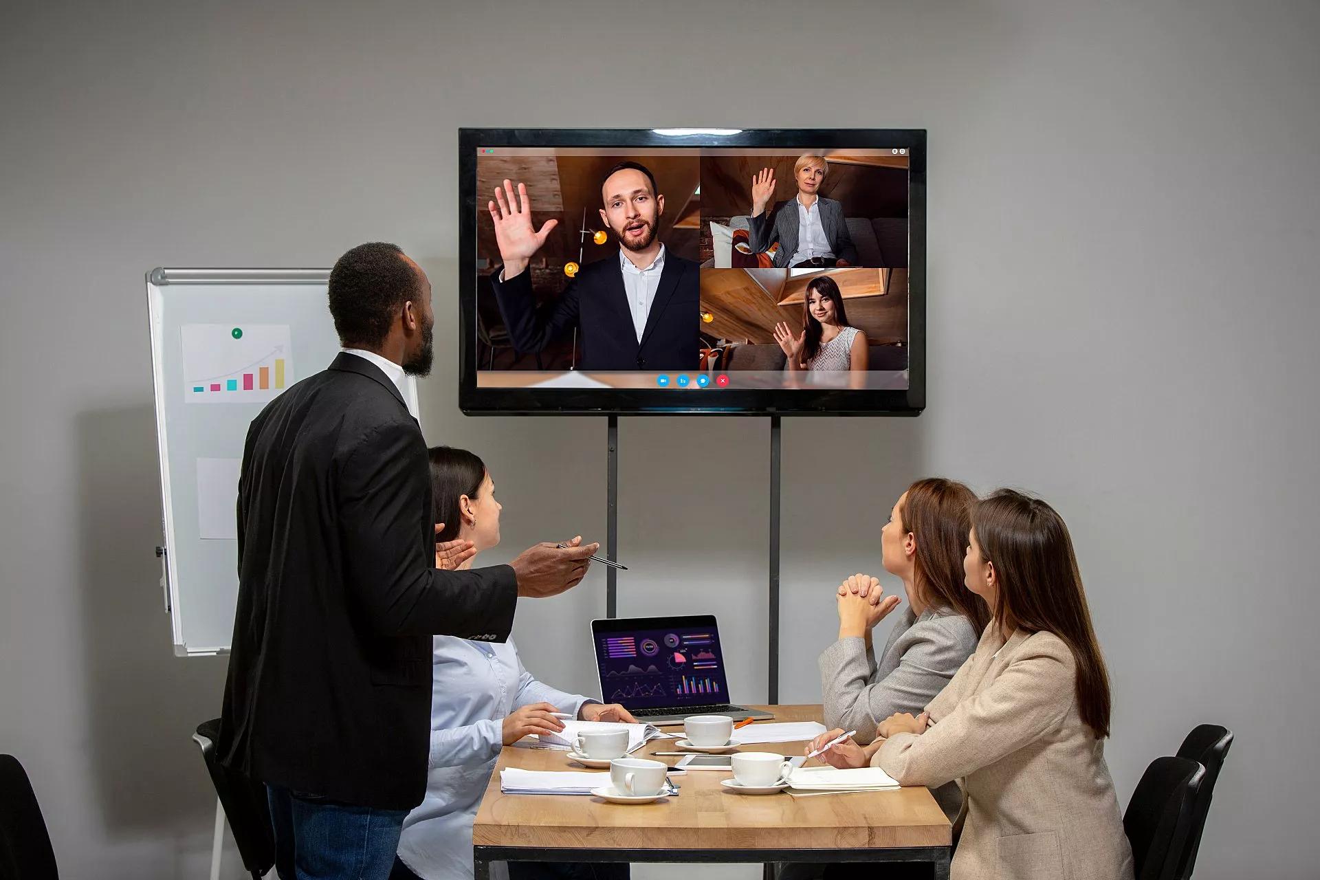 Employees in a conference room use hybrid work technology.
