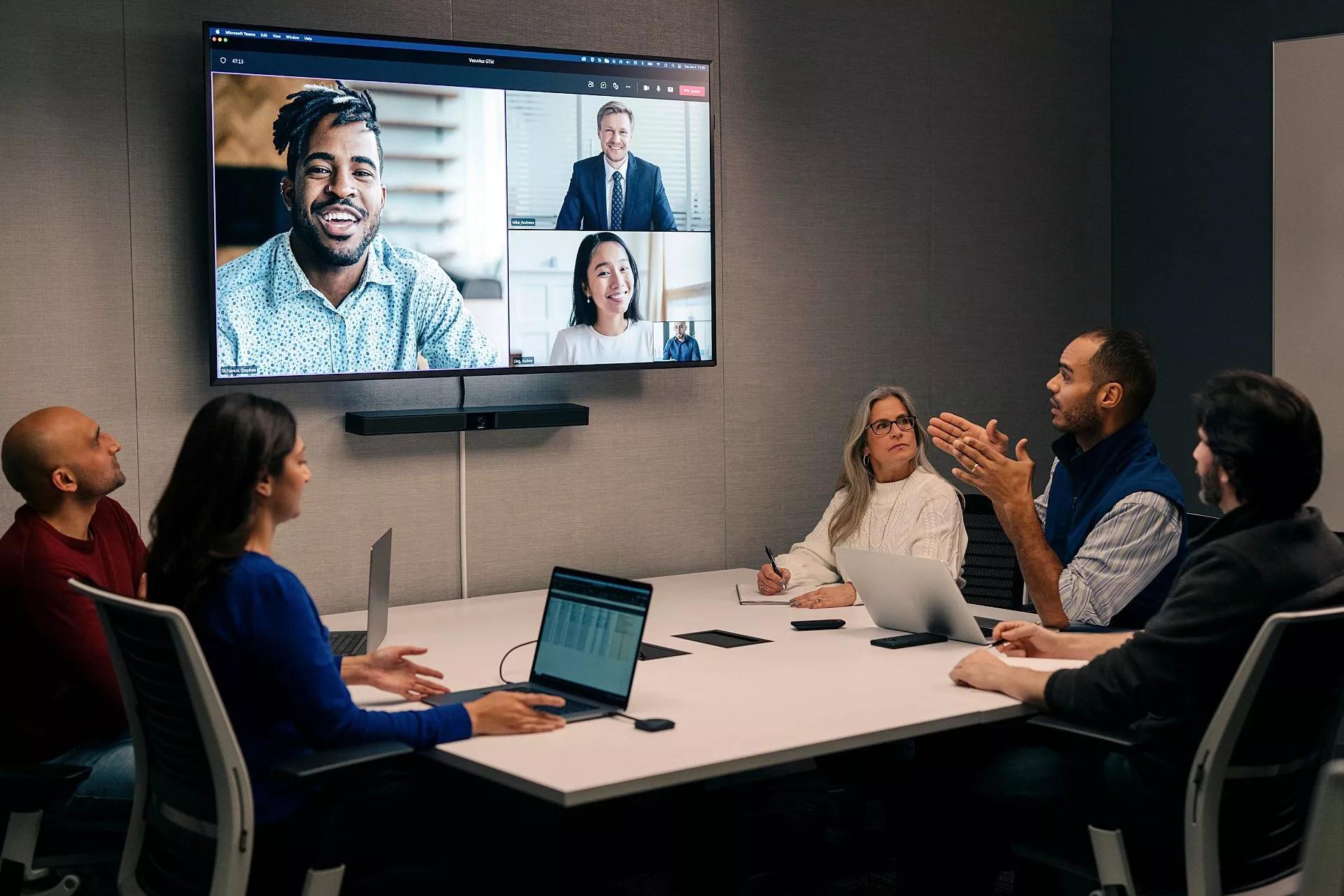 Two groups of employees speak to each other through video conferencing.