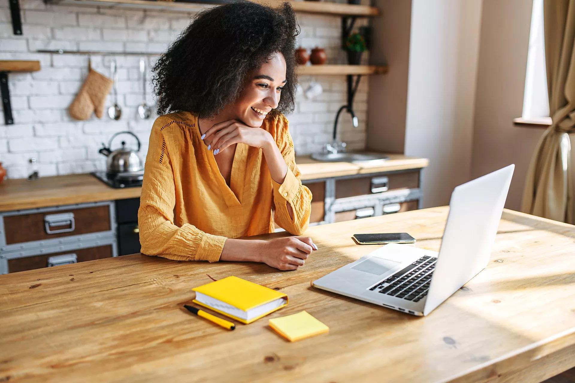 A woman joins a conference call with colleagues via laptop from her home office.