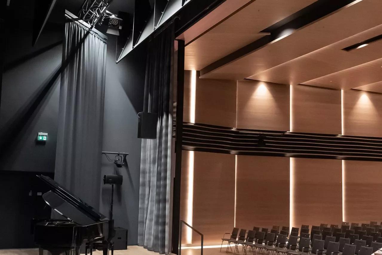 Un escenario de sala de conciertos con piano y equipo de audio.